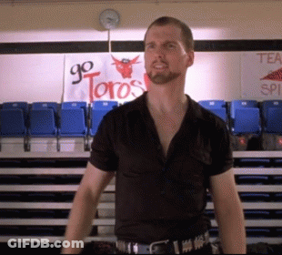 A Man In A Black Shirt Stands In Front Of A Sign That Says Go Toros GIF