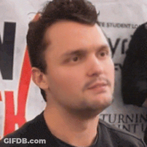 A Man In A Black Shirt Stands In Front Of A Sign That Says Turn GIF