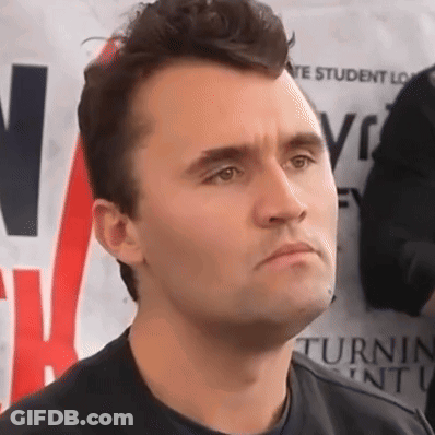 A Man In A Black Shirt Stands In Front Of A Sign That Says Vote Student Loans GIF