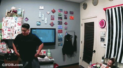 A Man In A Black Shirt Stands In Front Of A Television That Says ' Nintendo ' On The Screen GIF