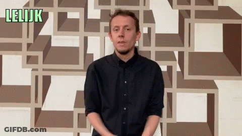 A Man In A Black Shirt Stands In Front Of A Wall That Has The Word Lelijk On It GIF