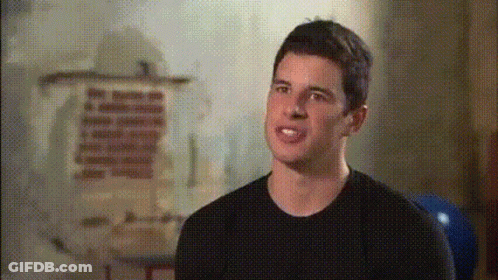 A Man In A Black Shirt Stands In Front Of A Wall With A Painting On It GIF