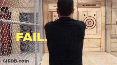 A Man In A Black Shirt Stands In Front Of A Wooden Target That Says Fail On It GIF