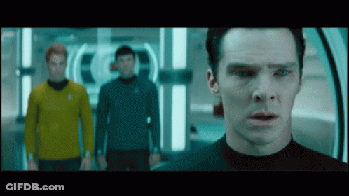 A Man In A Black Shirt Stands In Front Of Two Other Men GIF