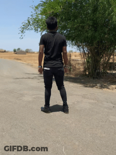 A Man In A Black Shirt Stands On The Side Of The Road GIF