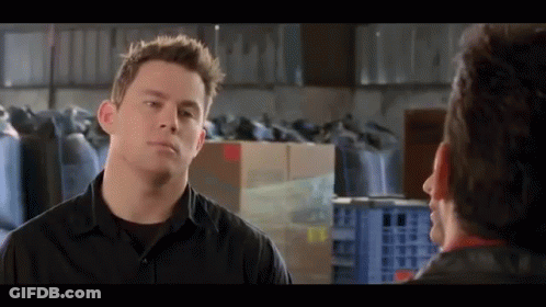 A Man In A Black Shirt Talks To Another Man In A Warehouse . GIF