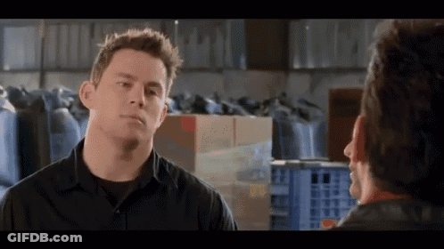 A Man In A Black Shirt Talks To Another Man In A Warehouse . GIF