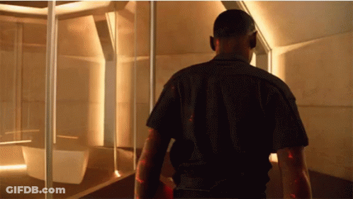 A Man In A Black Shirt Walks Through A Room GIF