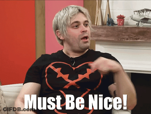 A Man In A Black Shirt With A Heart On It Says Must Be Nice GIF