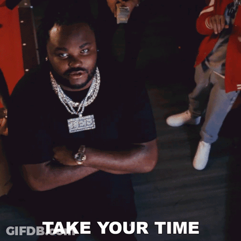 A Man In A Black Shirt With A Necklace That Says Take Your Time GIF