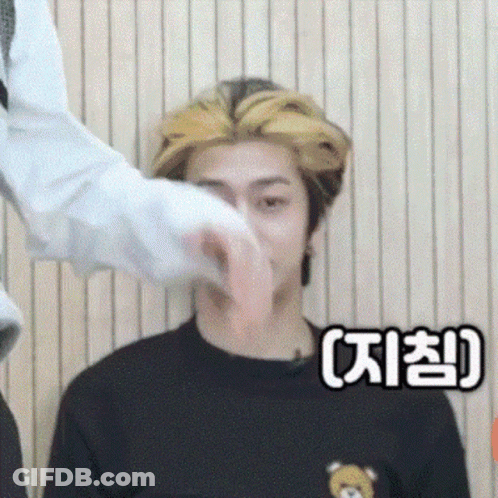 A Man In A Black Shirt With A Teddy Bear On It Is Being Touched By Another Man . GIF