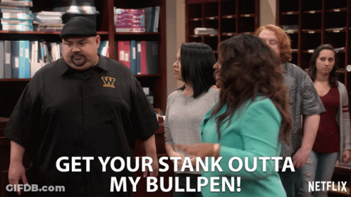 A Man In A Black Shirt With The Letter W On It Stands In Front Of A Group Of People GIF