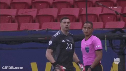 A Man In A Black Shirt With The Number 20 On It Is Standing Next To Another Man In A Pink Shirt GIF