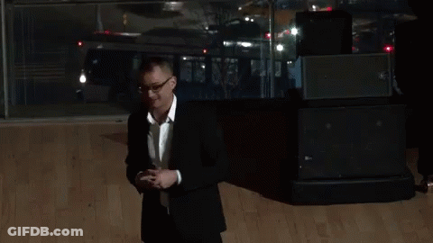 A Man In A Black Suit And White Shirt Is Giving The Peace Sign GIF