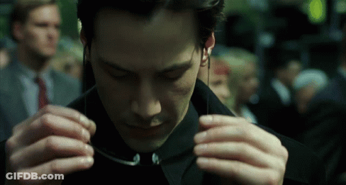 A Man In A Black Suit Is Adjusting His Sunglasses GIF