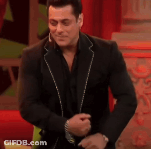 A Man In A Black Suit Is Dancing And Smiling . GIF