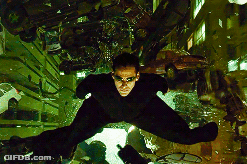 A Man In A Black Suit Is Flying Through The Air In A City GIF