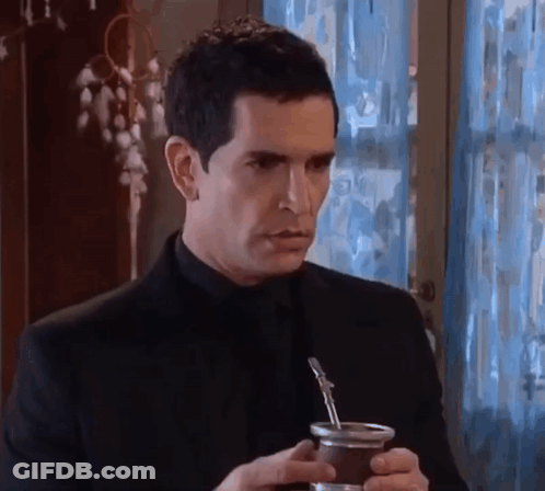 A Man In A Black Suit Is Holding A Cup Of Yerba Mate . GIF