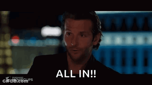 A Man In A Black Suit Is Holding A Glass Of Wine And Says `` All In '' . GIF