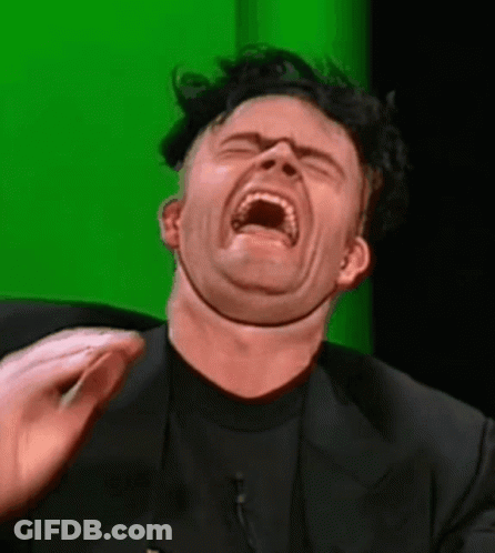 A Man In A Black Suit Is Making A Funny Face GIF