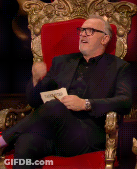 A Man In A Black Suit Is Sitting In A Red Chair GIF