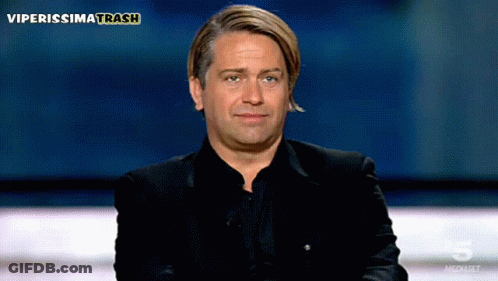 A Man In A Black Suit Is Sitting In Front Of A Screen That Says Viperissimo Trash GIF