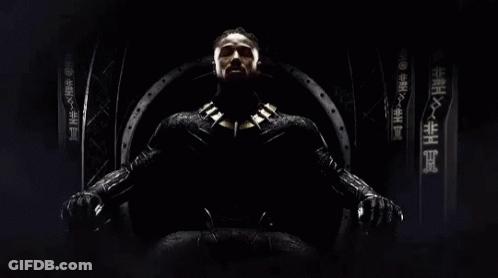 A Man In A Black Suit Is Sitting On A Throne With Chinese Writing On The Wall Behind Him GIF
