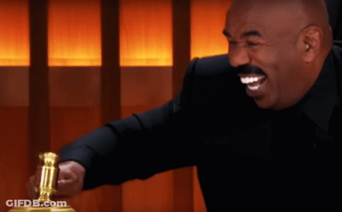 A Man In A Black Suit Is Smiling And Holding A Gold Hammer GIF