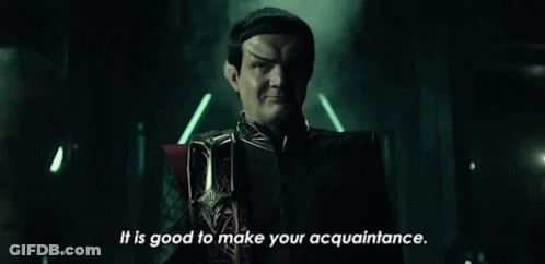 A Man In A Black Suit Is Standing In A Dark Room . GIF