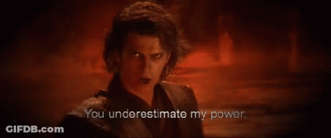 A Man In A Black Suit Is Standing In A Dark Room With A Red Background . GIF