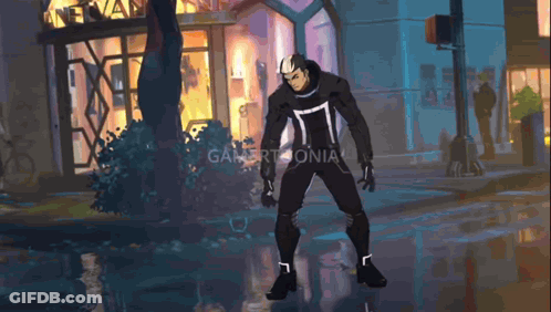 A Man In A Black Suit Is Standing In Front Of A Building That Says Gamertomania GIF