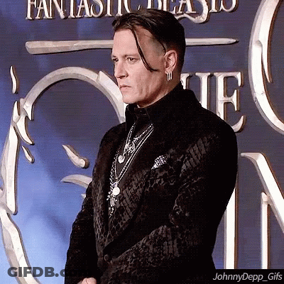 A Man In A Black Suit Is Standing In Front Of A Fantastic Beasts Sign GIF