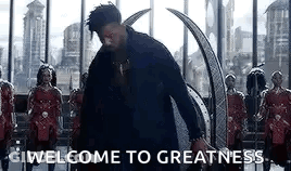 A Man In A Black Suit Is Standing In Front Of A Group Of Soldiers And Says Welcome To Greatness . GIF