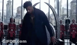 A Man In A Black Suit Is Standing In Front Of A Group Of Soldiers In A Room . GIF