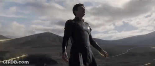 A Man In A Black Suit Is Standing In Front Of A Mountain Range In A Desert . GIF