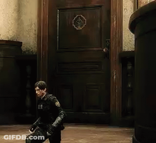 A Man In A Black Suit Is Standing In Front Of A Wooden Door In A Room . GIF