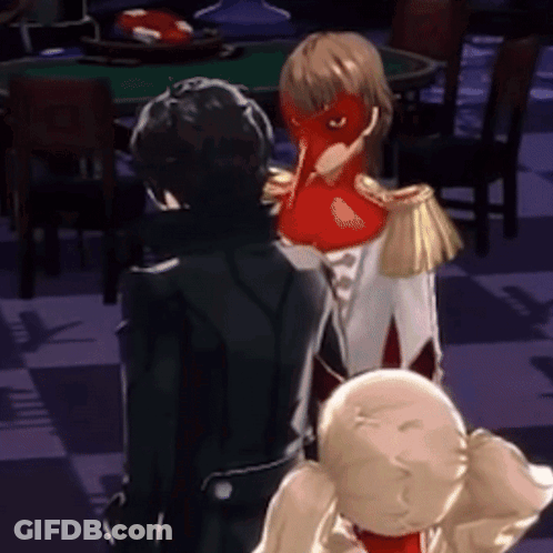 A Man In A Black Suit Is Standing Next To A Woman In A Red Mask .. GIF