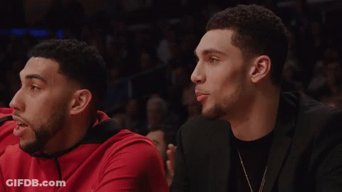 A Man In A Black Suit Sits Next To A Man In A Red Shirt GIF