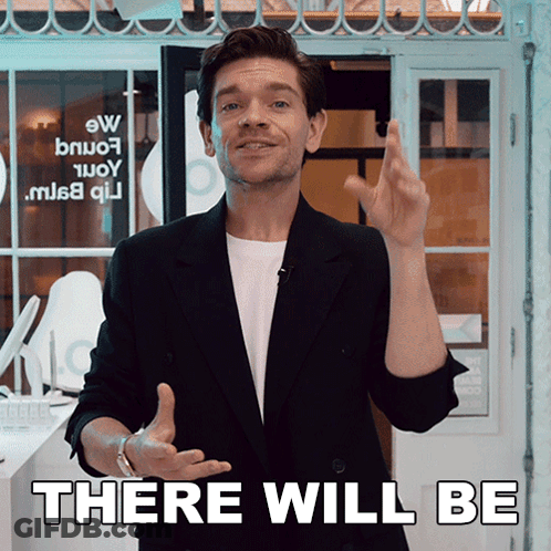A Man In A Black Suit Stands In Front Of A Sign That Says " There Will Be " GIF