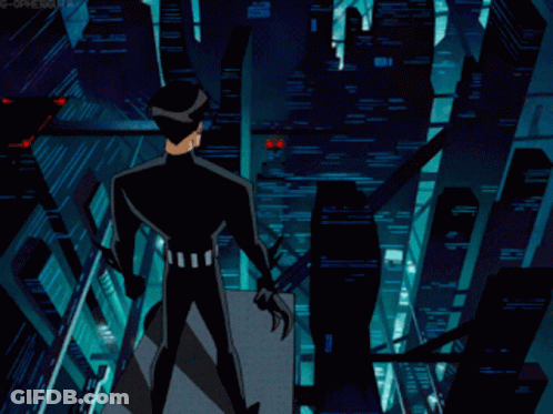 A Man In A Black Suit Stands On A Balcony Overlooking A City At Night GIF