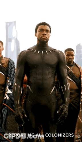A Man In A Black Suit With The Words Reporting All Colonizers Behind Him GIF