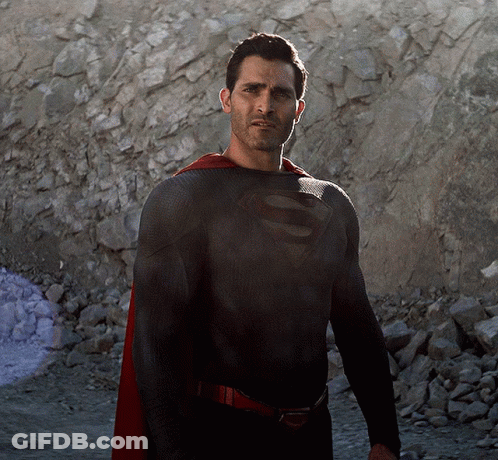 A Man In A Black Superman Costume With A Red Cape GIF