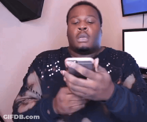 A Man In A Black Sweater Is Holding A Cell Phone GIF