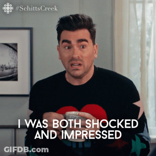 A Man In A Black Sweater Is Holding A Cup And Says I Was Both Shocked And Impressed GIF