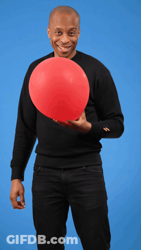 A Man In A Black Sweater Is Holding A Large Red Balloon GIF