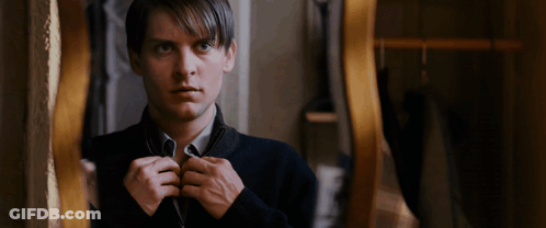 A Man In A Black Sweater Is Looking At Himself In A Mirror GIF
