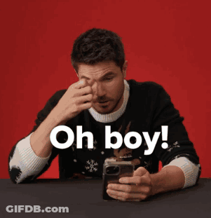 A Man In A Black Sweater Is Looking At His Phone And Says Oh Boy GIF
