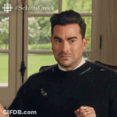 A Man In A Black Sweater Is Sitting In Front Of A Window And Making A Face . GIF
