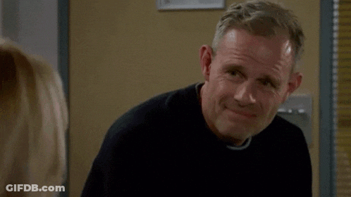 A Man In A Black Sweater Is Smiling While Looking At A Woman GIF