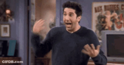 A Man In A Black Sweater Is Standing In A Living Room With His Mouth Open And His Hands Outstretched . GIF